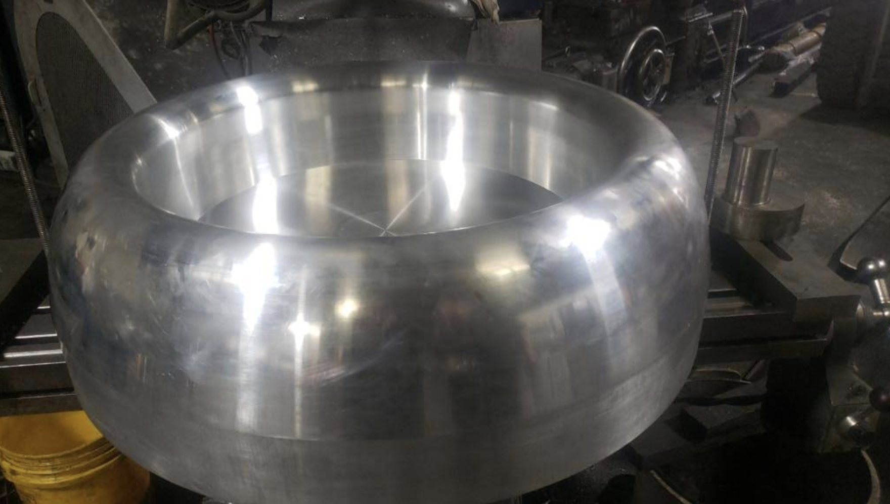 Large bowl-shaped turned metal component on a lathe