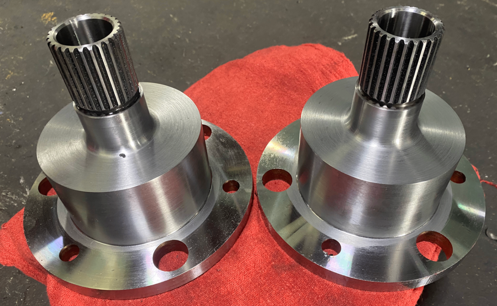 Pair of splined machined hubs on a red cloth